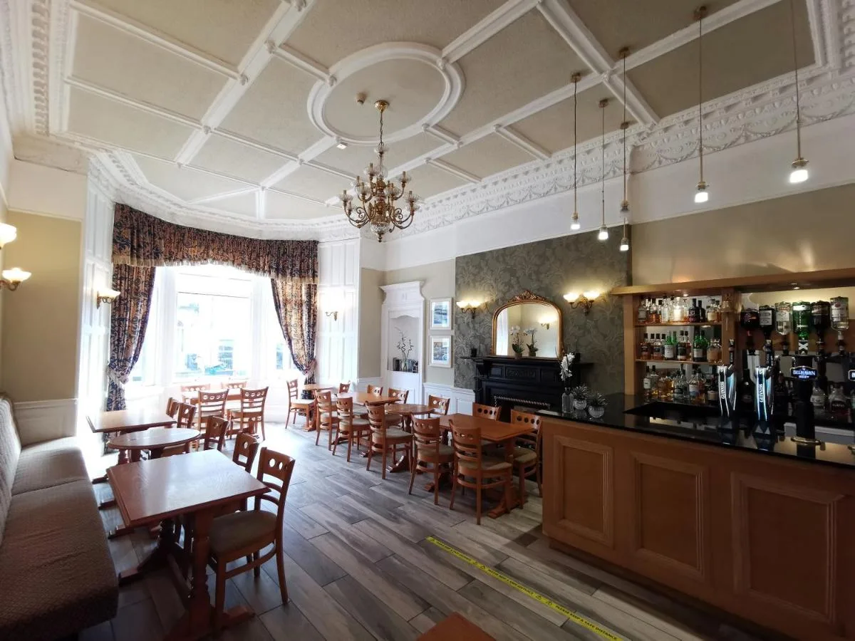 a restaurant with wooden tables and chairs and a bar at The Haymarket Hotel in Edinburgh