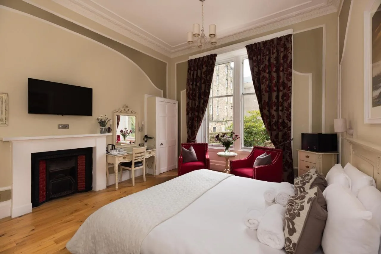 a bedroom with a white bed and a fireplace at The Haymarket Hotel in Edinburgh