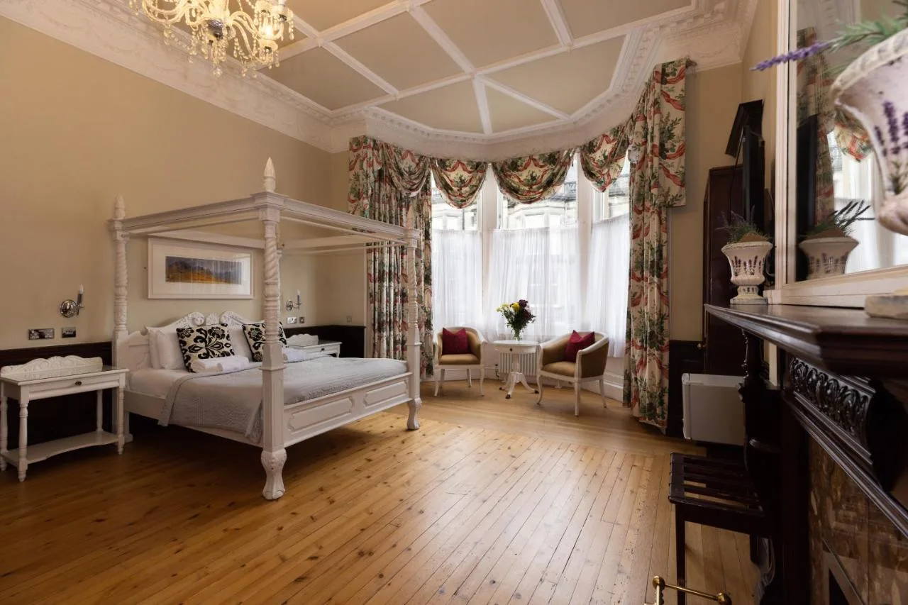 a bedroom with a canopy bed and a living room at The Haymarket Hotel in Edinburgh