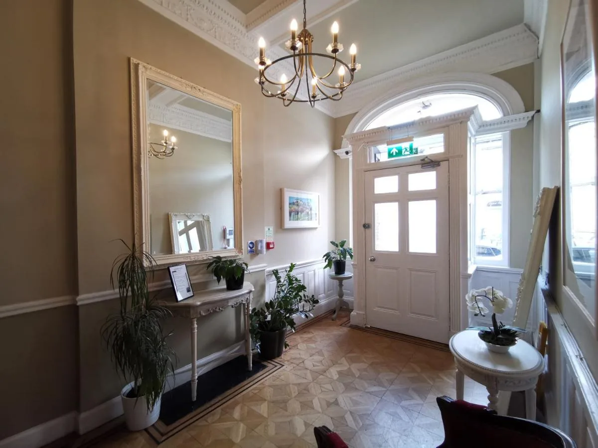 a hallway with a mirror and a door with plants at The Haymarket Hotel in Edinburgh