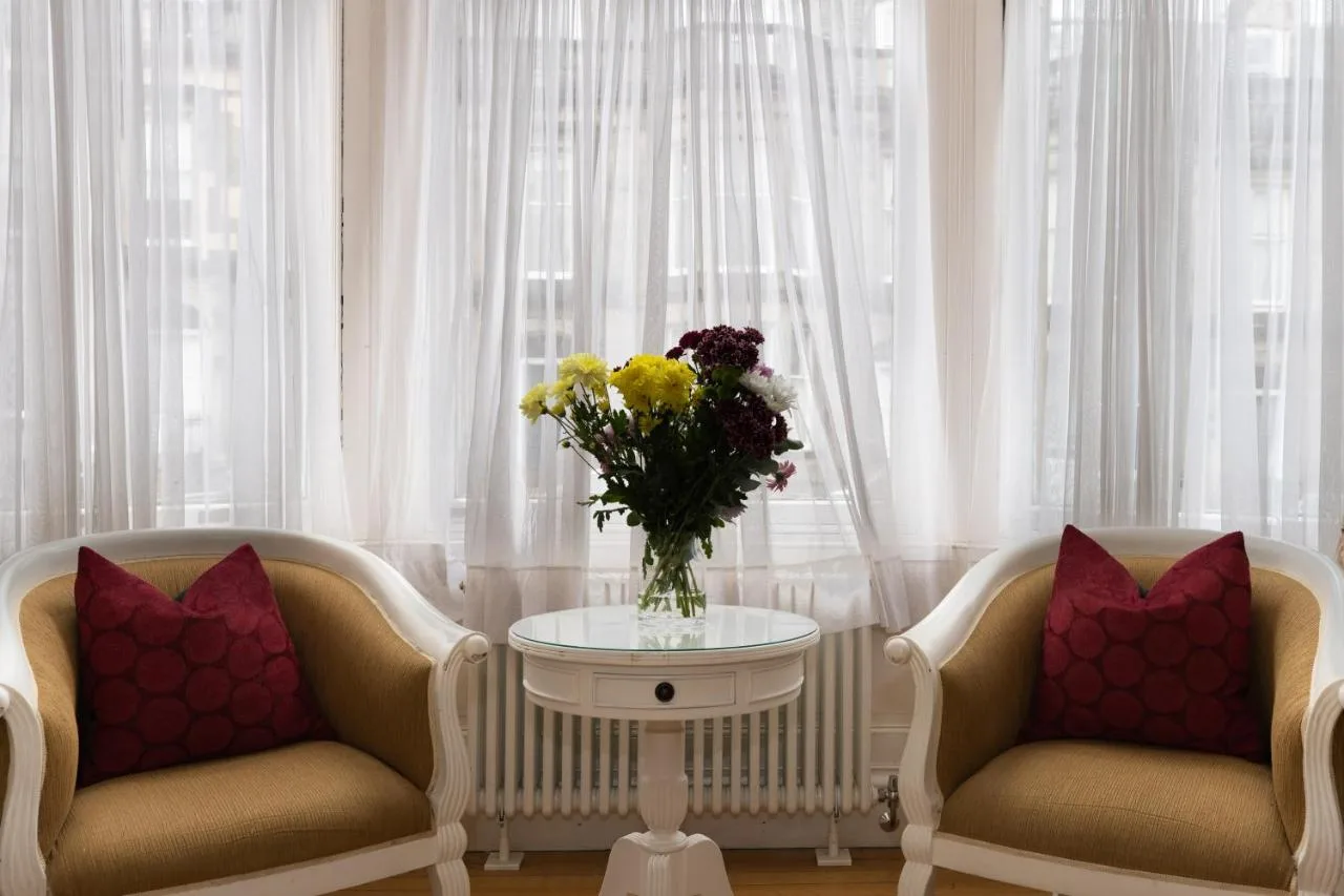two chairs and a table with a vase of flowers at The Haymarket Hotel in Edinburgh